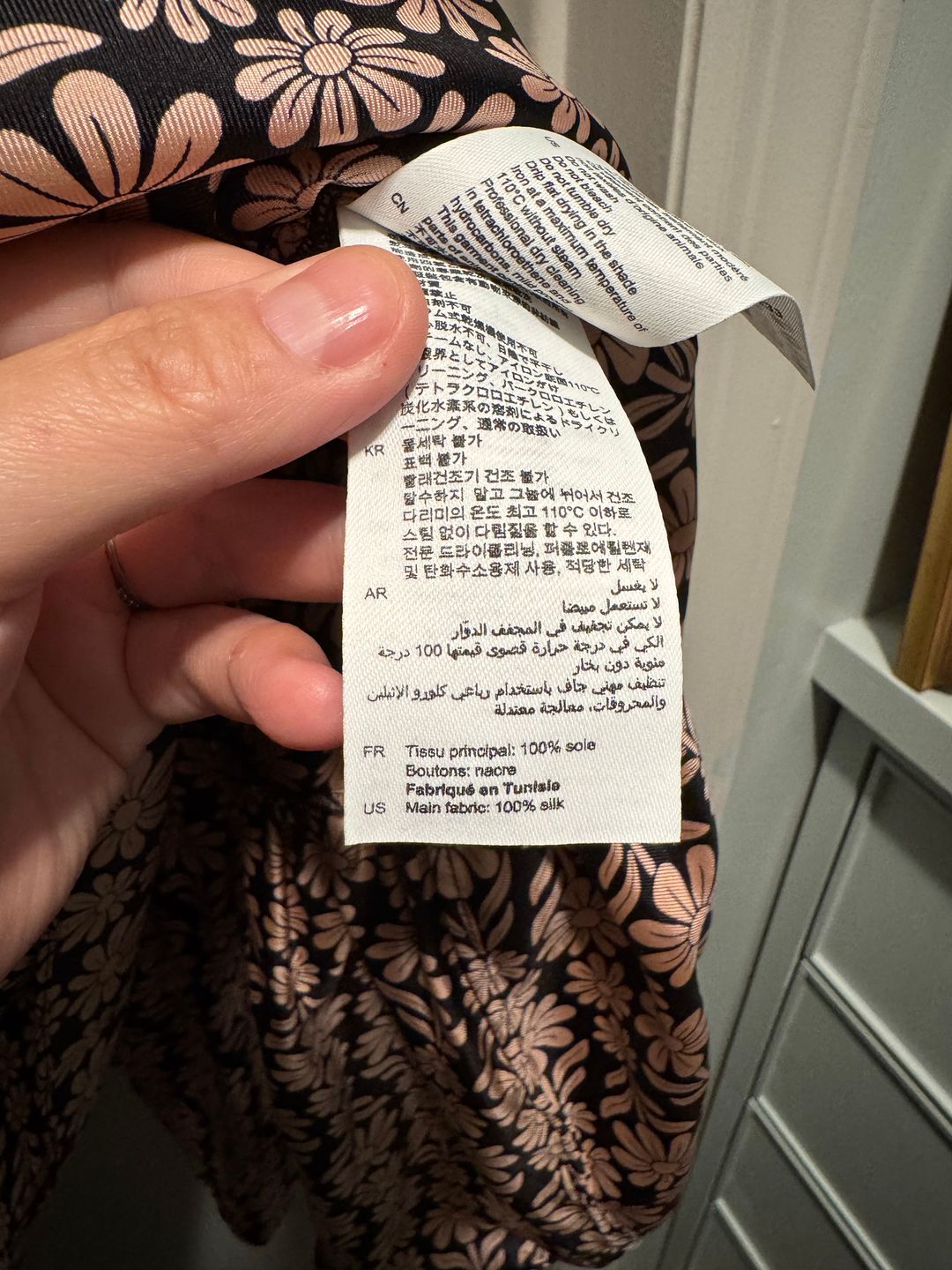 Sandro Drop waist silk mini dress with pink daisies against dark navy. Long sleeves, gold button